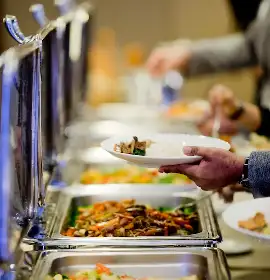 Guest being served from chafing dishes at a wedding buffet